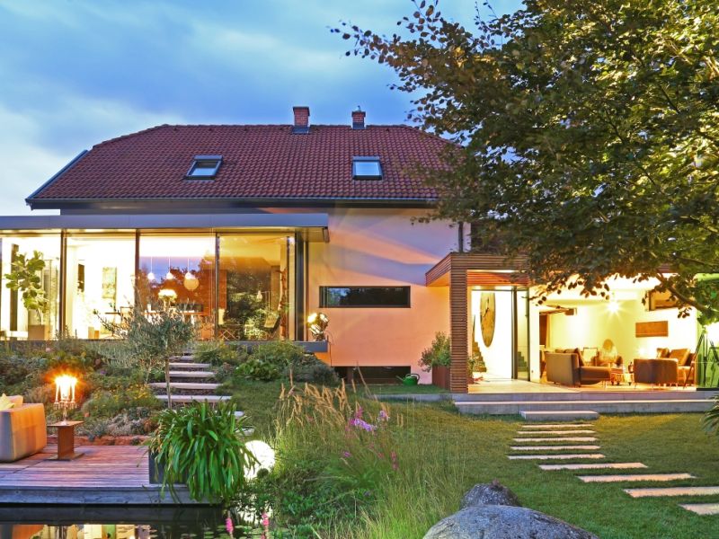 In der Dämmerung ein gut beleuchtets Haus mit viel Glas