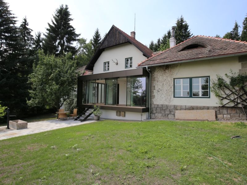 Mitten im Wald ein kleines Haus mit einem Wintergarten für viel Transparenz 