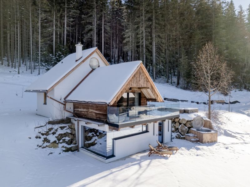 Eine Berghütte in einer verschneiten Umgebung wo sich die Landschaft widerspiegelt 